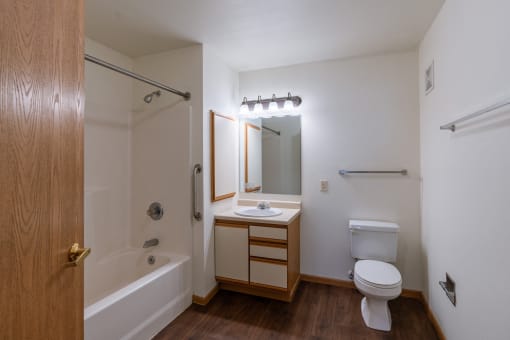 a bathroom with a toilet and a sink and a bath tub. Grand Forks, ND Autumn Ridge Apartments