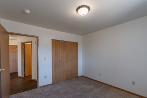 a bedroom with carpet and a door to a bedroom. Grand Forks, ND Autumn Ridge Apartments