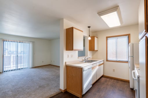 an empty kitchen and living room with a refrigerator and a sink. Grand Forks, ND Autumn Ridge Apartments