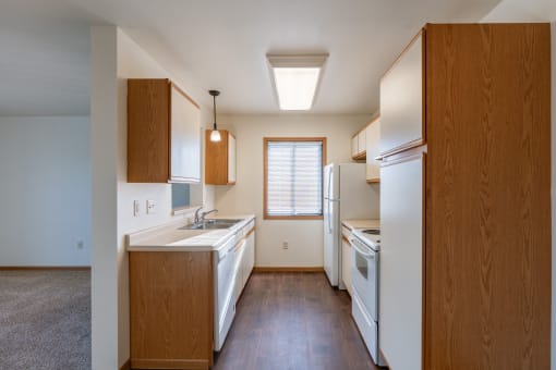 an empty kitchen with white appliances and wooden cabinets. Grand Forks, ND Autumn Ridge Apartments