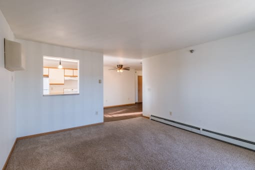 a living room with white walls and carpet and a door to a kitchen. Grand Forks, ND Autumn Ridge Apartments