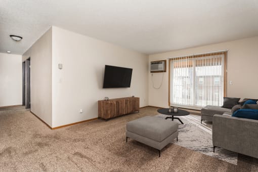 Grand Forks, ND Barrette Arms Apartments.  a living room with a couch and a chair and a tv on the wall