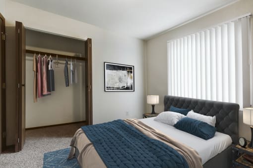 Grand Forks, ND Carling Manor Apartments.  a bedroom with a large bed and a closet with a sliding door and a window