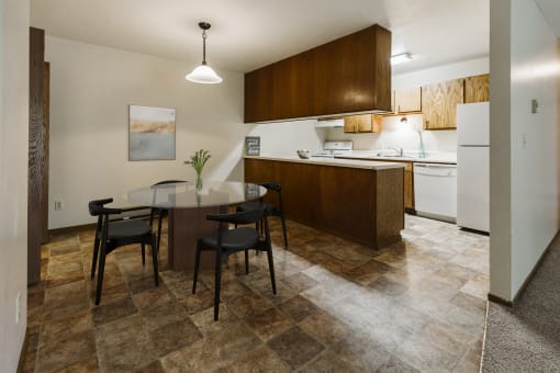 Grand Forks, ND Carling Manor Apartments.  a dining area with a table and chairs and a kitchen in the background