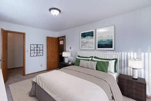 a bedroom with a bed and two lamps and a door to a bathroom. Grand Forks, ND Cedarwood Apartments