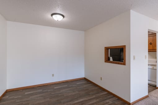 the living room and dining room of an apartment with a wood floor and white walls. Grand Forks, ND Cedarwood Apartments