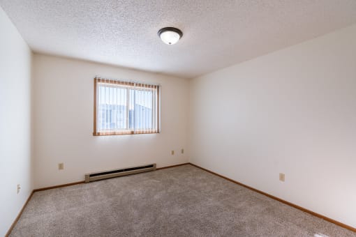 a bedroom with carpet and a window. Grand Forks, ND Chandler 1866 Apartments