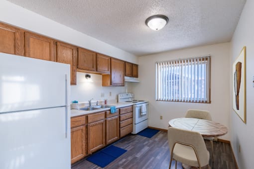 a kitchen with a dining table and a refrigerator. Grand Forks, ND Chandler 1866 Apartments