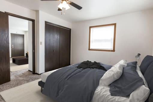 Grand Forks, ND Claremont Apartments. a bedroom with a bed and a ceiling fan