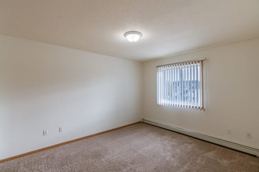 Grand Forks, ND Creekside Apartments. A bedroom with carpeted floors and a window.