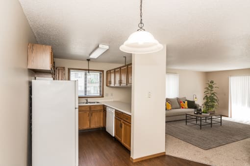 A kitchen with white appliances and living room with a couch and a coffee table in the background at Harrison and Richfield, Grand Forks, North Dakota