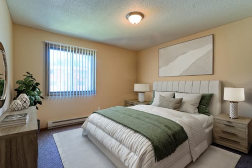 a bedroom with bed, dresser, and a window. Grand Forks, ND Madison Apartments