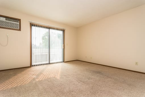 Grand Forks Ridgemont Apartments. A living room with a glass sliding door and an air conditioner on the wall
