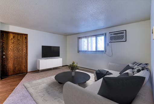 Grand Forks, ND Roughrider Apartments. a living room with white walls and a tv on the wall