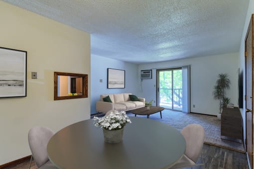 Grand Forks, ND Roughrider Apartments. a dining area with a table and chairs and a couch in the background