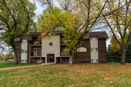 Grand Forks, ND Roughrider Apartments. The exterior of  a three level apartment building with a sidewalk leading to the front door.
