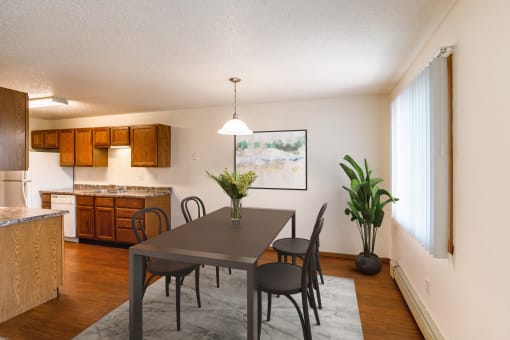 A dining room and kitchen with a table and chairs. Grand Forks, ND Southview Apartments.