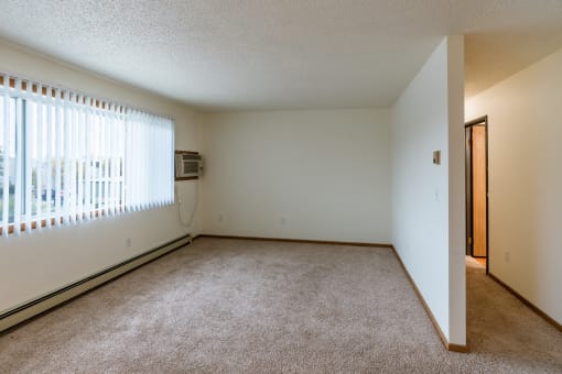Grand Forks, ND Southview III Apartments. A living room of an apartment with carpet and a window