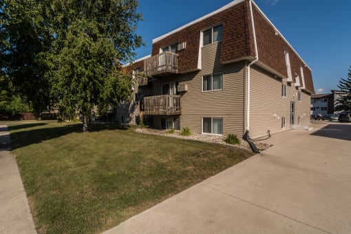 Grand Forks, ND Stanford Apartments. an apartment building with balconies and a large lawn