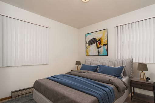 Grand Forks, ND Valley Home Duplex. a bedroom with two windows and a bed with a gray blanket and blue pillows