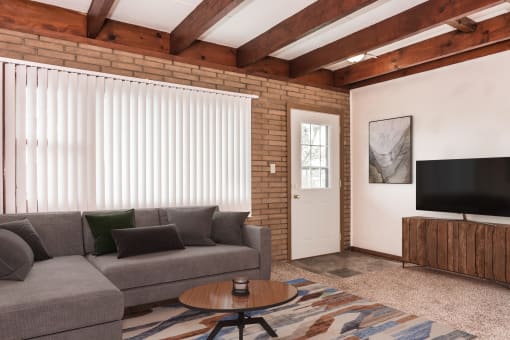 Grand Forks, ND Washington Apartments. A small living room with a couch and a coffee table near a large window and the front door