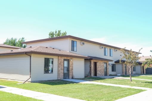 a white house with a yard and a sidewalk. Fargo, ND Hazelwood Townhomes