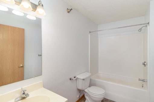 a bathroom with a toilet and a tub and a sink. Hutchinson, MN Deer Park Apartments