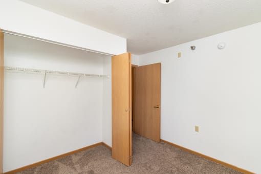 an empty bedroom with a closet and a door to the bathroom. Hutchinson, MN Deer Park Apartments