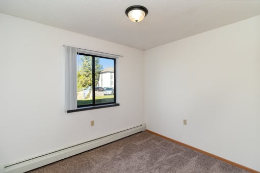 an empty room with a window and a carpet. Hutchinson, MN Deer Park Apartments