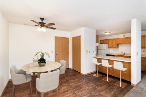 a dining room with a table and chairs and a kitchen. Hutchinson, MN Deer Park Apartments