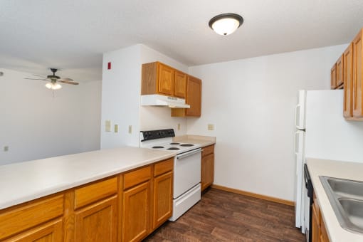an empty kitchen with white appliances and wooden cabinets. Hutchinson, MN Deer Park Apartments
