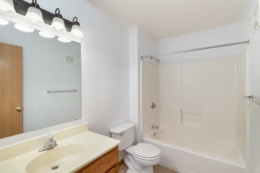 a bathroom with a sink toilet and shower and a mirror. Hutchinson, MN Deer Park Apartments