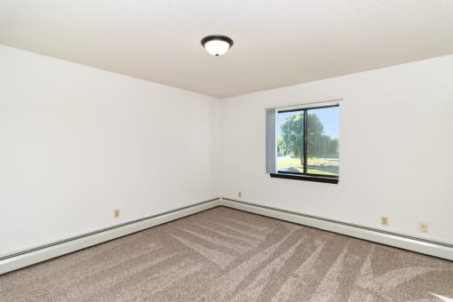 an empty room with carpet and a window. Hutchinson, MN Deer Park Apartments
