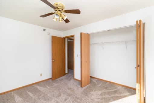 an empty bedroom with a ceiling fan and a closet. Hutchinson, MN Deer Park Apartments
