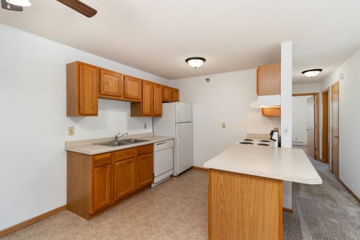 a kitchen with white appliances and wooden cabinets and a white counter top. Hutchinson, MN Deer Park Apartments