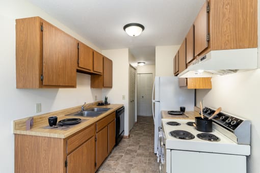 a kitchen with a stove and a sink and a refrigerator. Hutchinson, MN Echo Manor Apartments