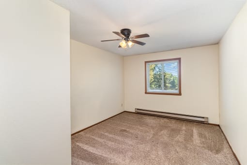 a bedroom with carpet and a ceiling fan. Hutchinson, MN Twin Oaks Townhomes