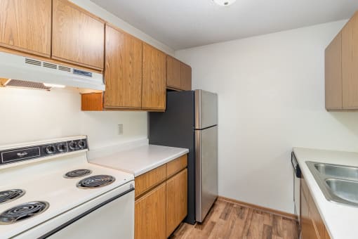 a kitchen with white appliances and wooden cabinets and a refrigerator. Hutchinson, MN Twin Oaks