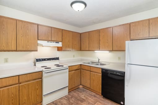 an empty kitchen with white appliances and wooden cabinets. Hutchinson, MN Twin Oaks Townhomes