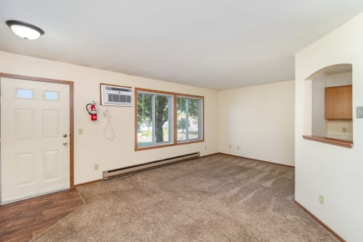 an empty living room with a white door and a window. Hutchinson, MN Twin Oaks Townhomes