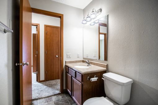 Bismarck, ND Eastbrook Apartments | A bathroom with a toilet sink and mirror