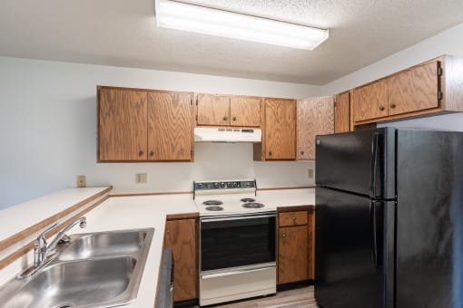 an empty kitchen with a stove refrigerator and sink. Fargo, ND Rosegate Apartments