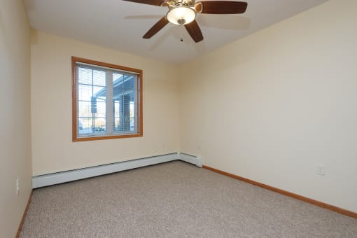 a bedroom with a window and a carpeted floor. Fargo, ND Crossroads Apartments