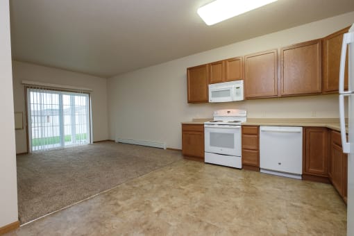 a kitchen with white appliances and wooden cabinets. Fargo, ND North Sky Apartments