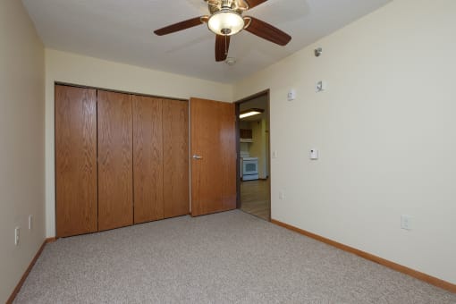 a bedroom with a closet and a door to a hallway. Fargo, ND Crossroads Apartments