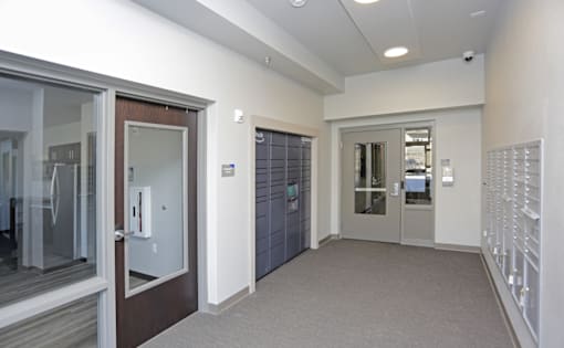A hallway with a white wall and a brown door. Fargo, ND 29 West Apartments