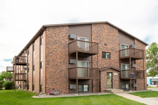 a brick apartment building with balconies and a bike parked outside. Fargo, ND Maplewood Bend Apartments