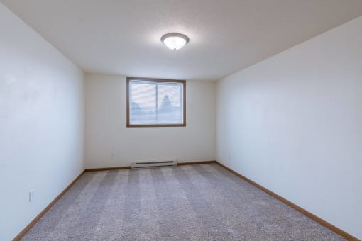 a bedroom with a window and carpet. Moorhead, MN South Park Apartments