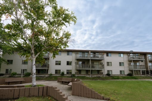 an apartment building with a lawn and a tree in front of it. Moorhead, MN South Park Apartments