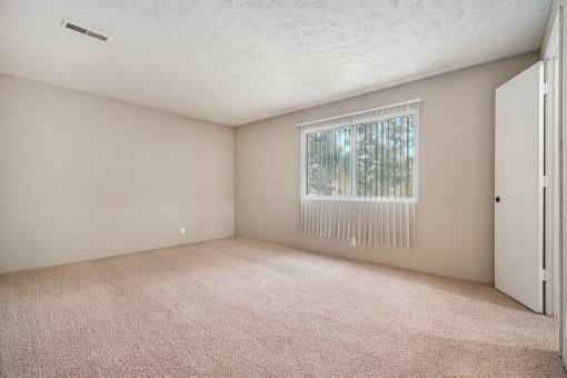 Omaha, NE Evergreen Terrace Apartments. A bedroom with a large window and beige carpet